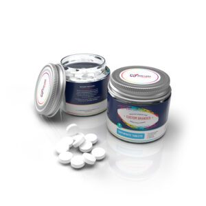 A jar and container of white tablets on a white surface.